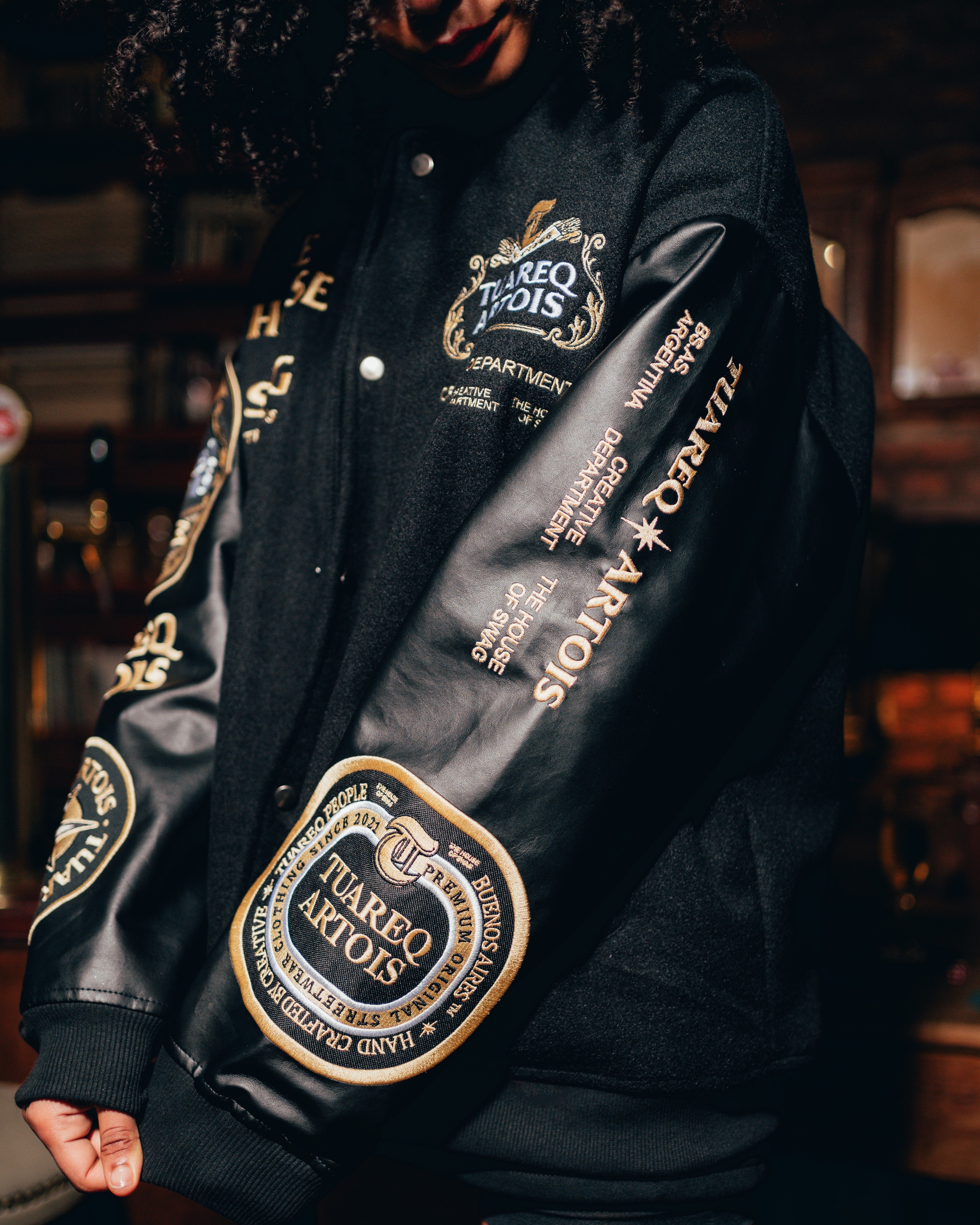 CAMPERA VARSITY [ STELLA ARTOIS ] BLACK & GOLD